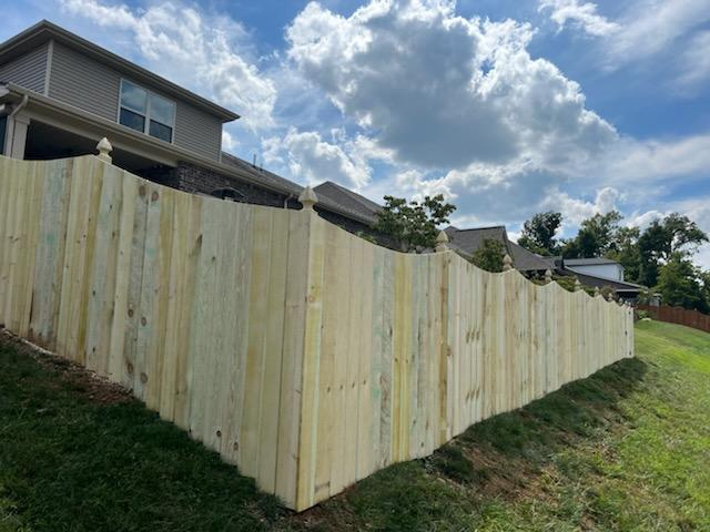 A wooden fence is sitting on top of a grassy hill next to a house. Clarksville, TN