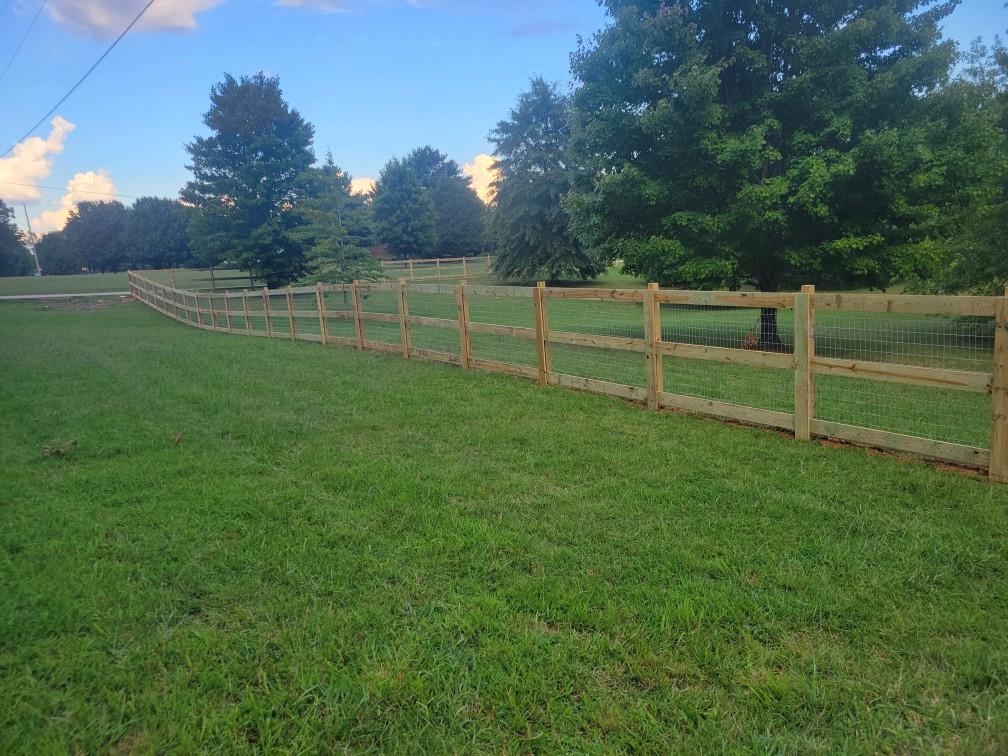 A wooden fence surrounds a grassy field with trees in the background. Clarksville, TN