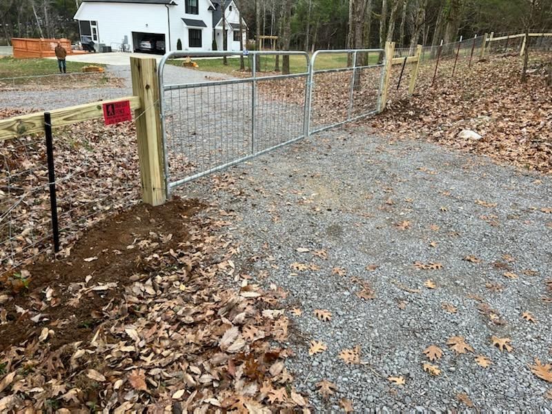 A metal gate is sitting on the side of a gravel road next to a wooden post. Clarksville, TN