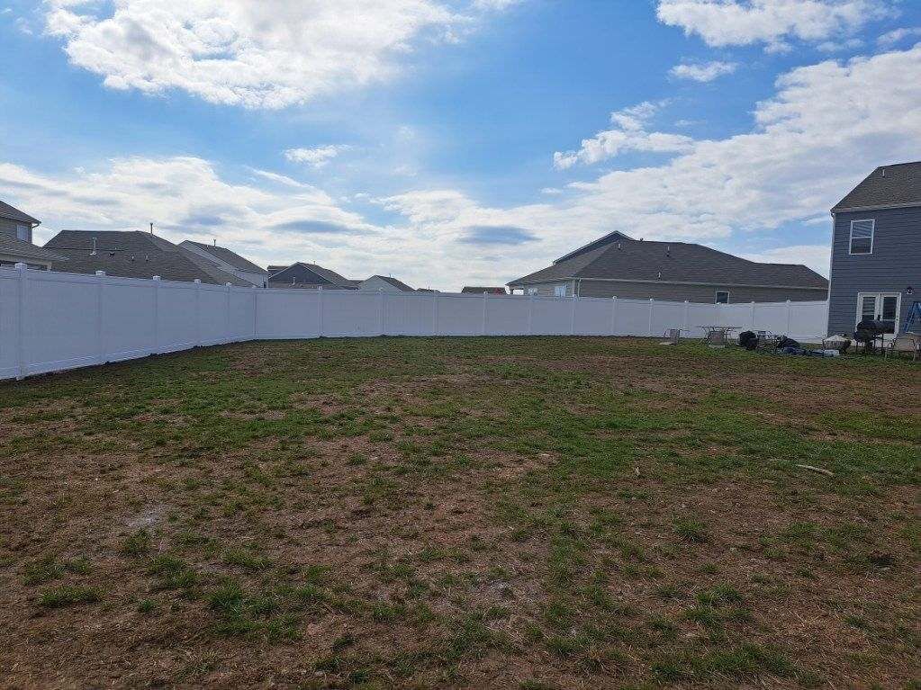 A white fence surrounds a lush green field with a house in the background. Middle, TN