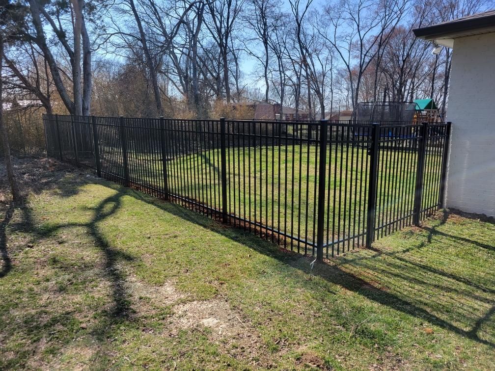A black metal fence surrounds a lush green yard. Middle, TN