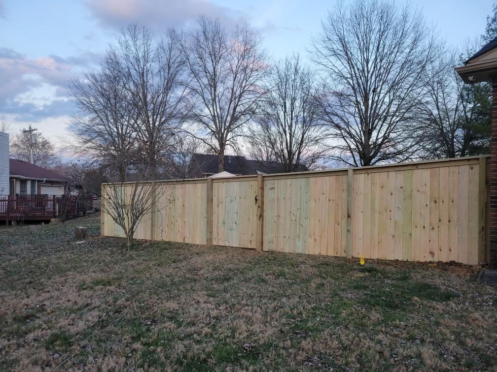 A wooden fence in a backyard with trees in the background. Middle, TN