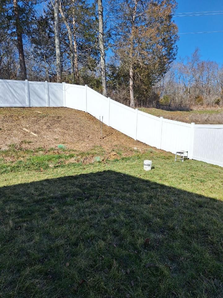 A white fence surrounds a lush green yard with trees in the background. Middle, TN