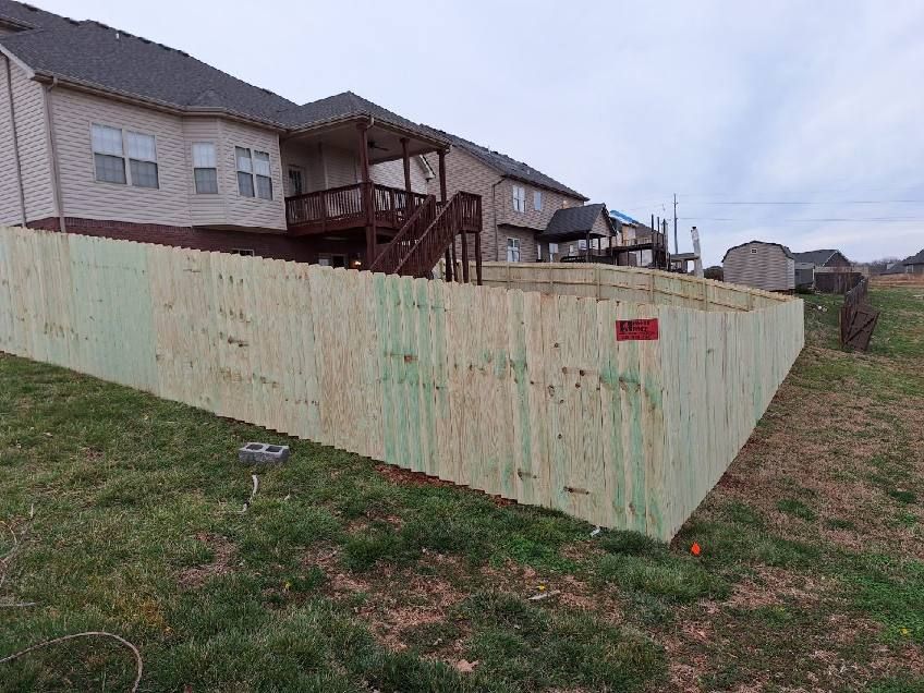A wooden fence is sitting in the grass in front of a house. Middle, TN