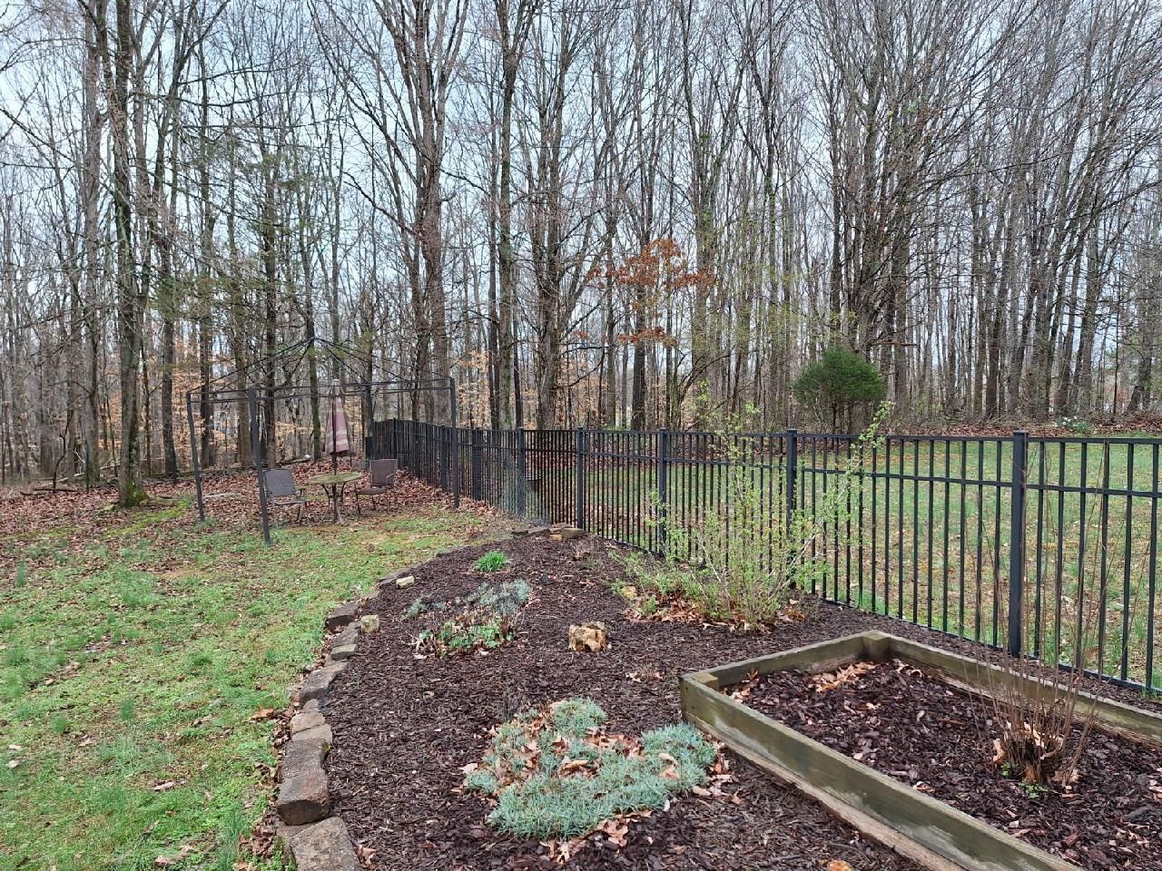 A garden with a fence and trees in the background. Middle, TN