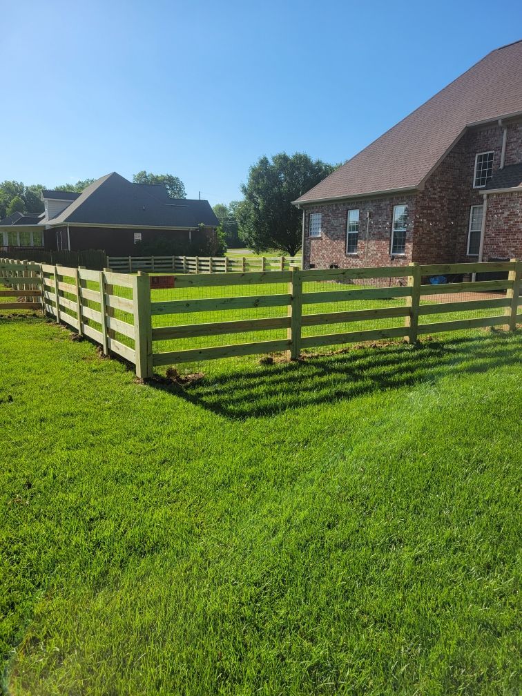 A wooden fence surrounds a lush green field in front of a house. Clarksville,TN