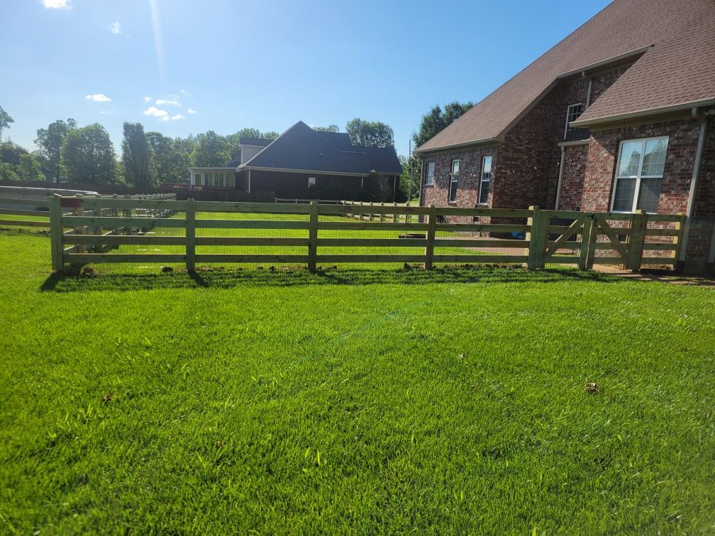 A wooden fence surrounds a lush green field in front of a house. Clarksville,TN