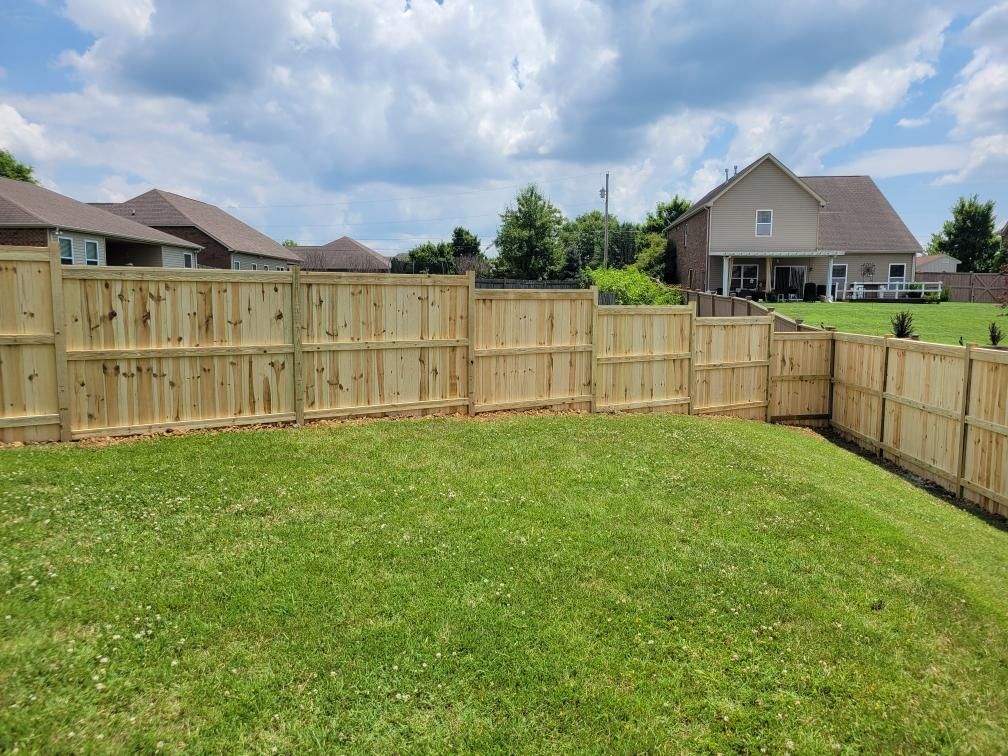 A wooden fence surrounds a lush green yard in front of a house. Clarksville, TN