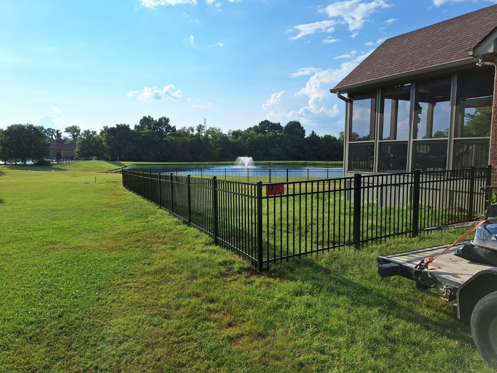 A metal fence surrounds a swimming pool in front of a house. Clarksville, TN