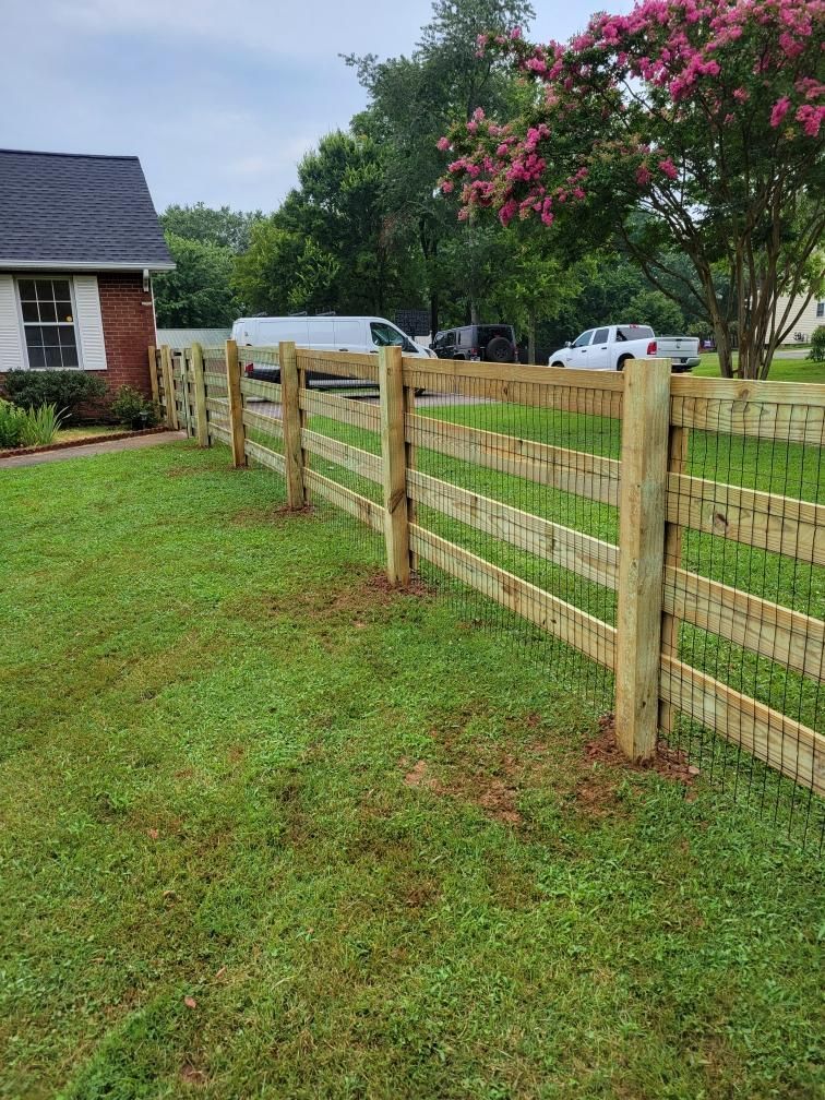 A wooden fence surrounds a lush green yard in front of a house. Middle, TN
