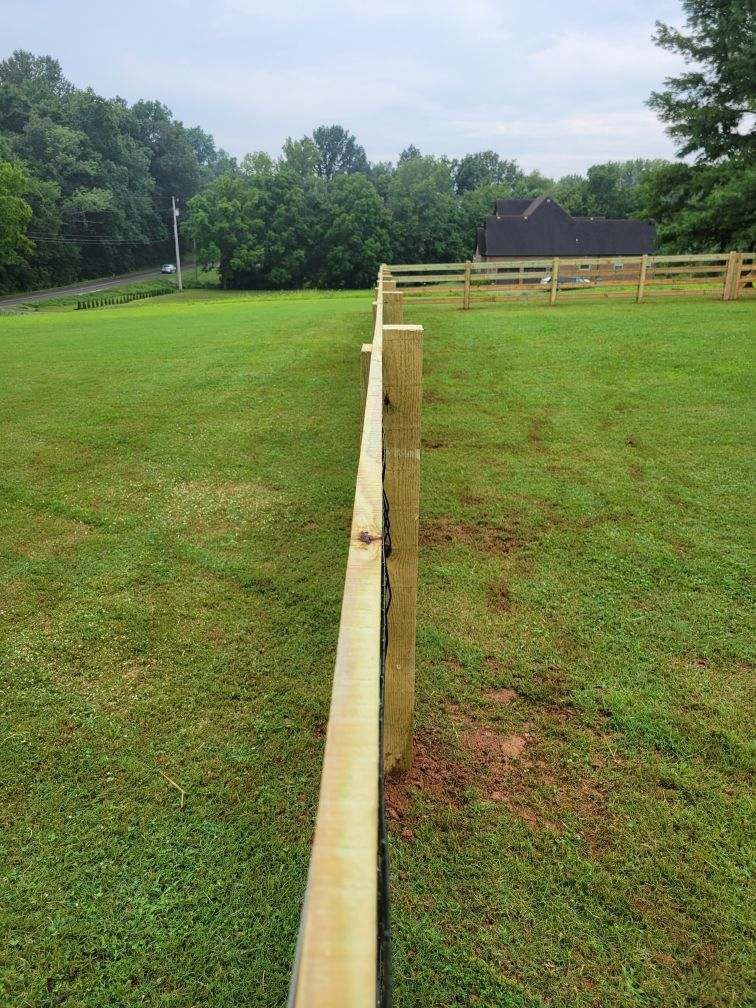 A wooden fence surrounds a lush green field. Middle, TN
