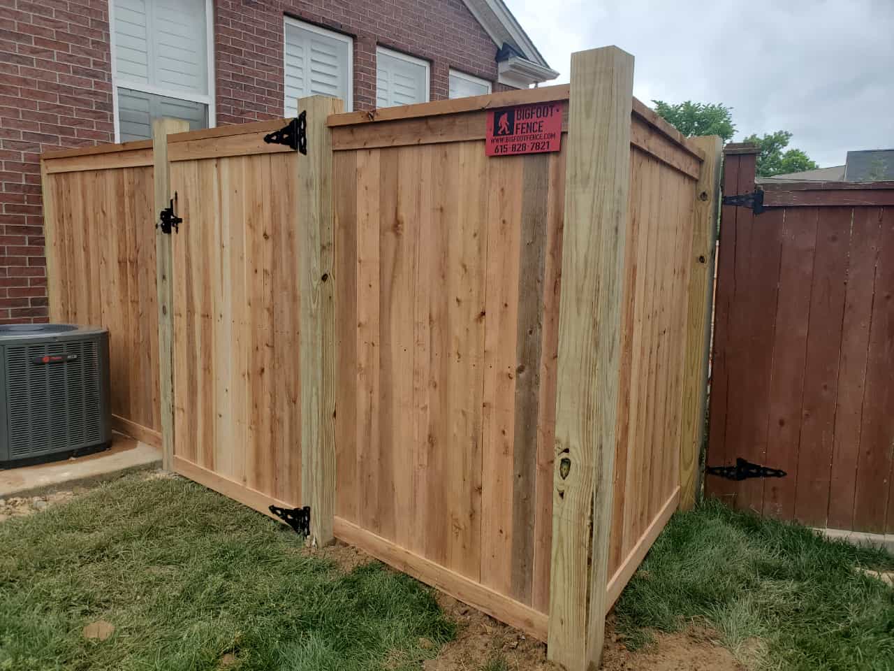 A wooden fence with a gate is in the backyard of a house. Middle, TN