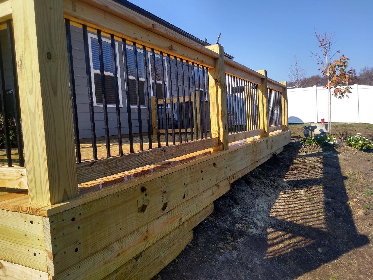 A wooden deck with a metal railing in front of a house. Middle, TN