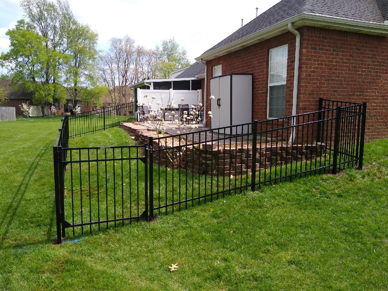 A black fence surrounds a patio area in front of a brick house. Middle, TN