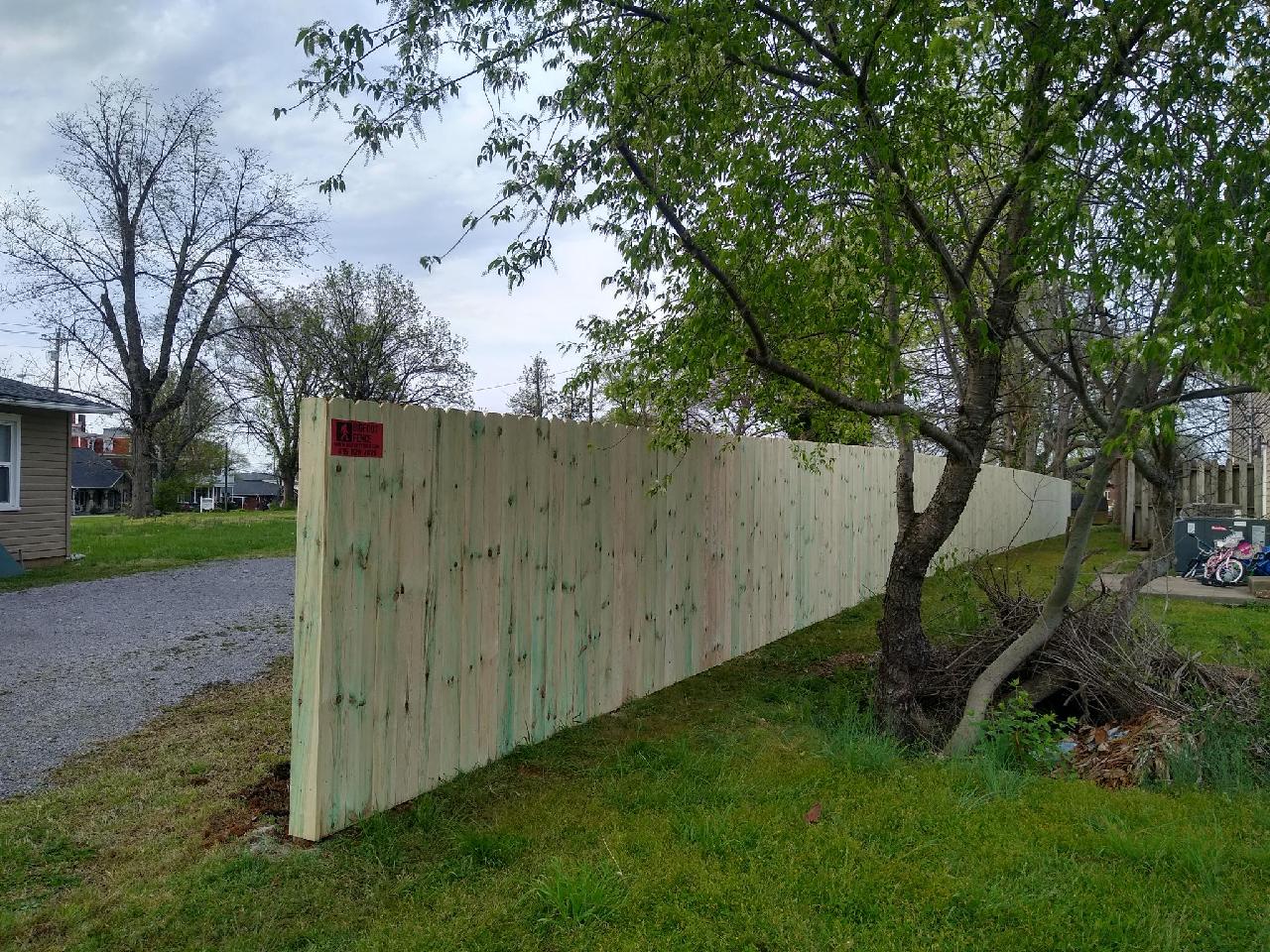 A wooden fence is surrounded by grass and trees in a yard. Middle, TN