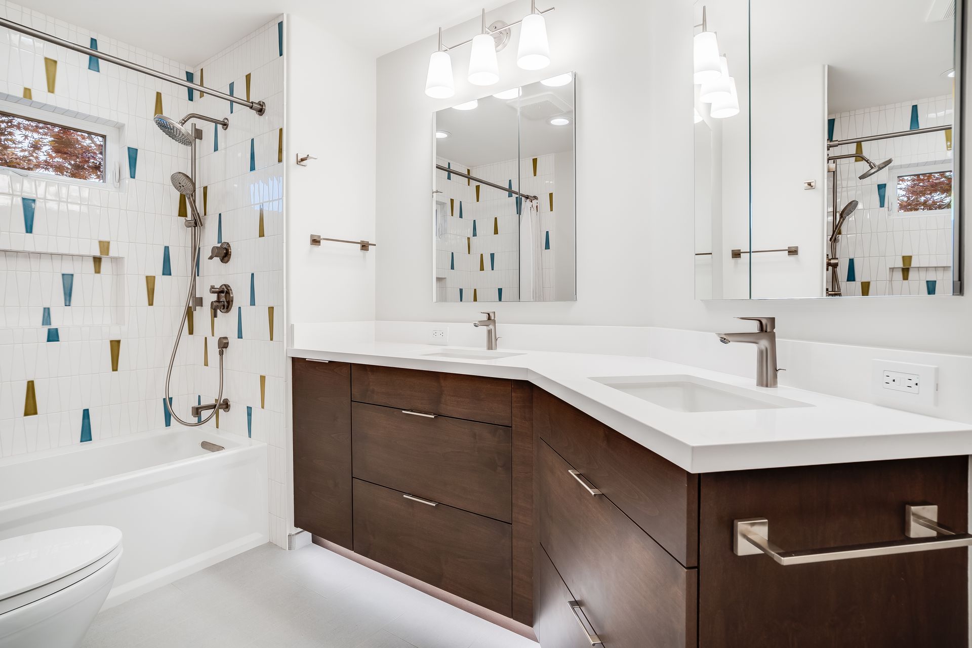 Modern bathroom with brown vanity, white countertops, colorful tile, and chrome fixtures.