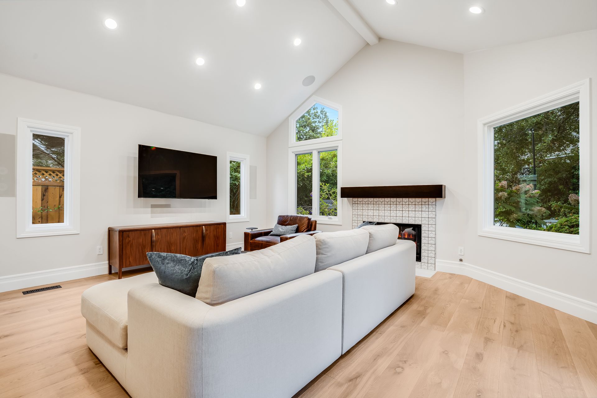 Bright living room with white walls, hardwood floors, modern furniture, and large windows.