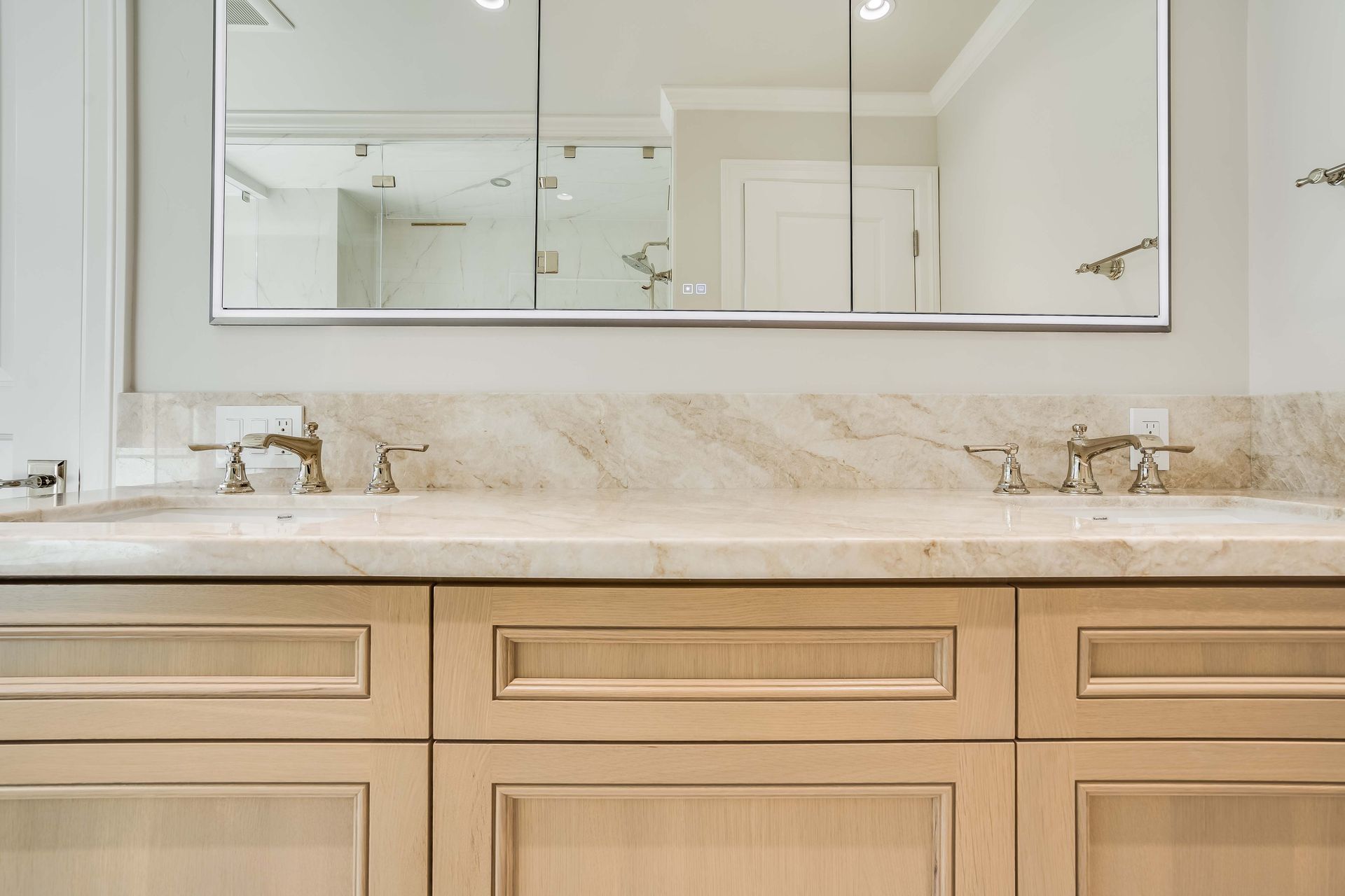 Bathroom vanity with double sinks, neutral-toned cabinetry, and a mirrored medicine cabinet.