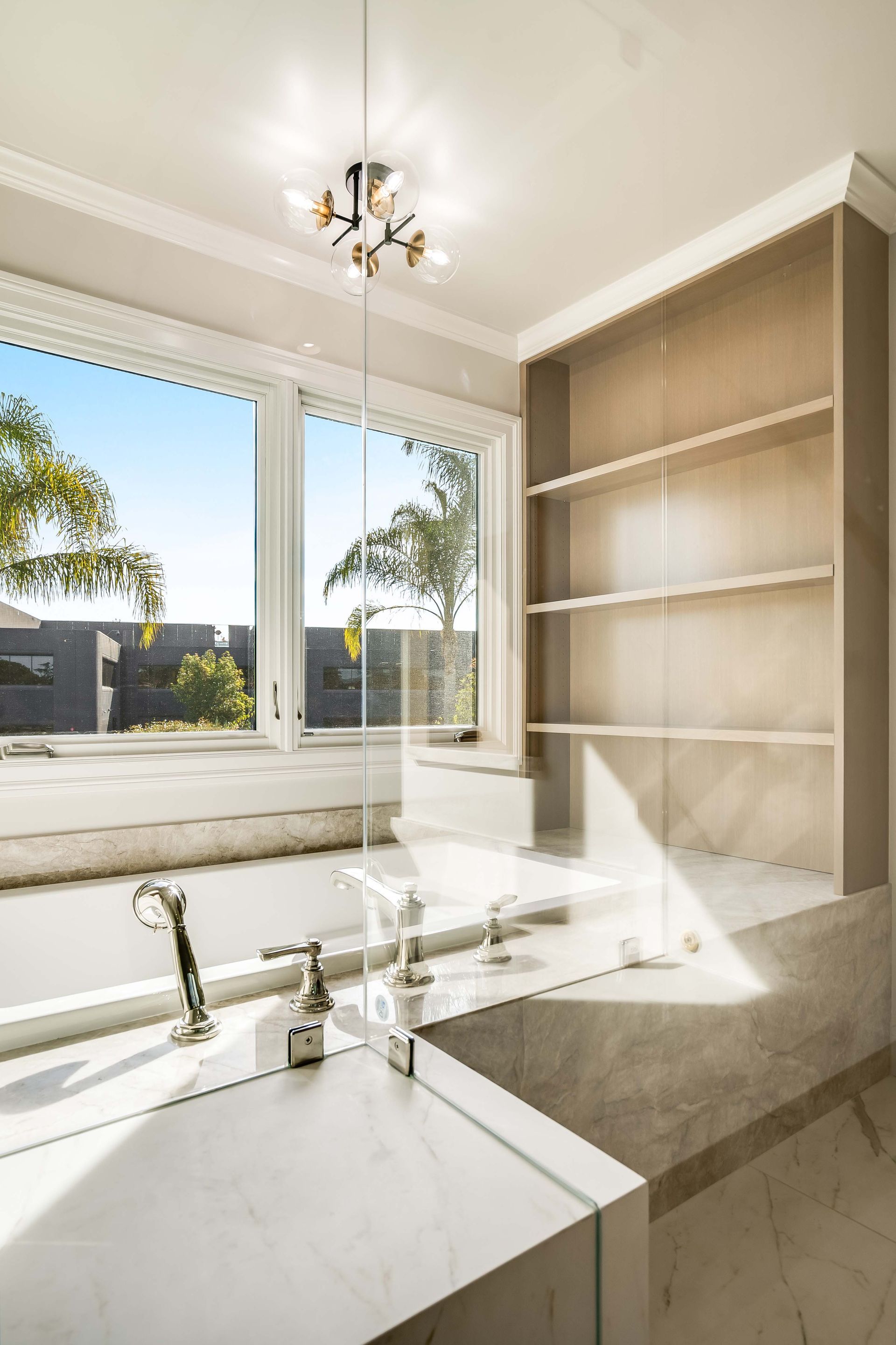 Bright bathroom with a window, built-in shelving, and a modern light fixture.