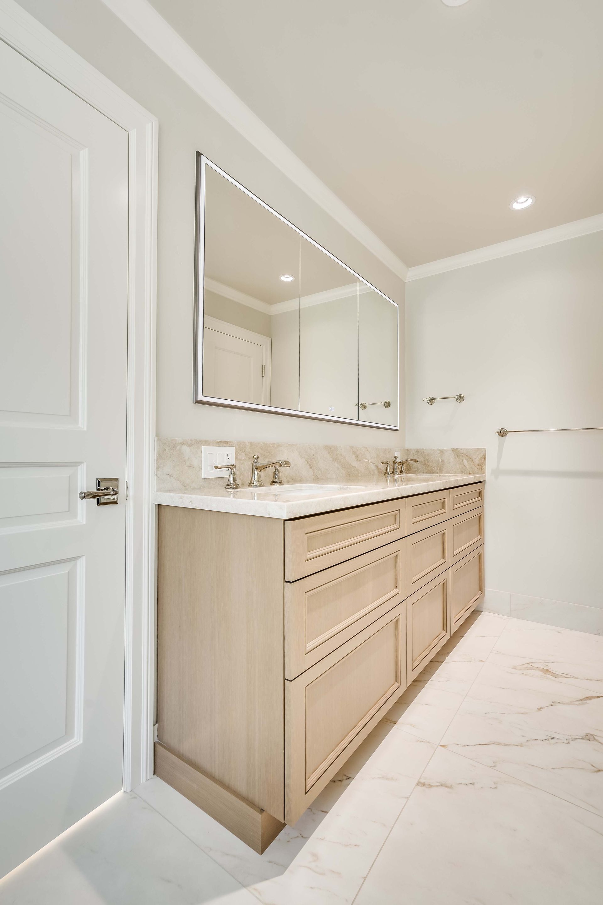 Bathroom with a double vanity, large mirror, and white and beige tones.
