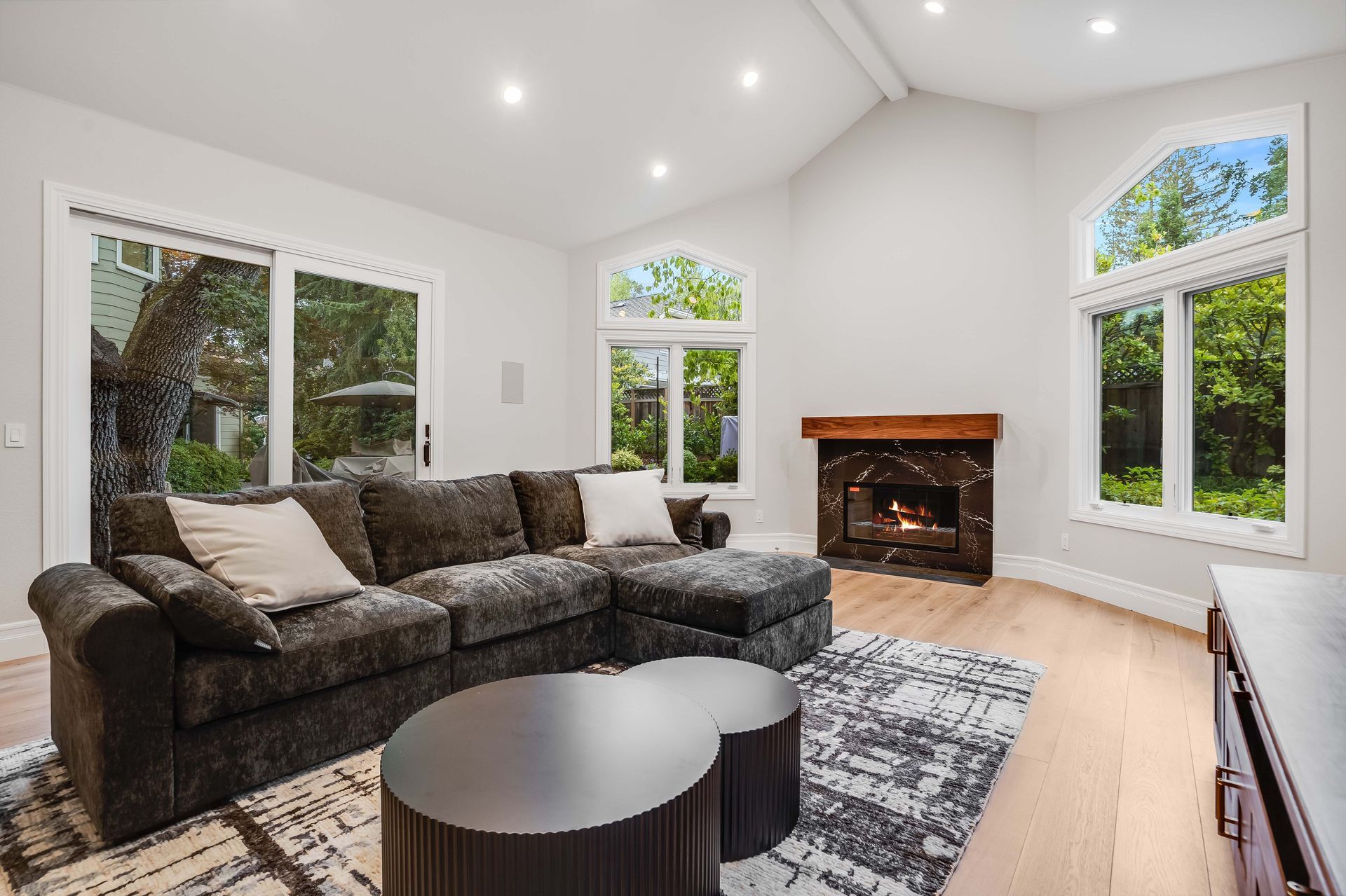 Living room with dark gray sectional sofa, fireplace, and large windows.