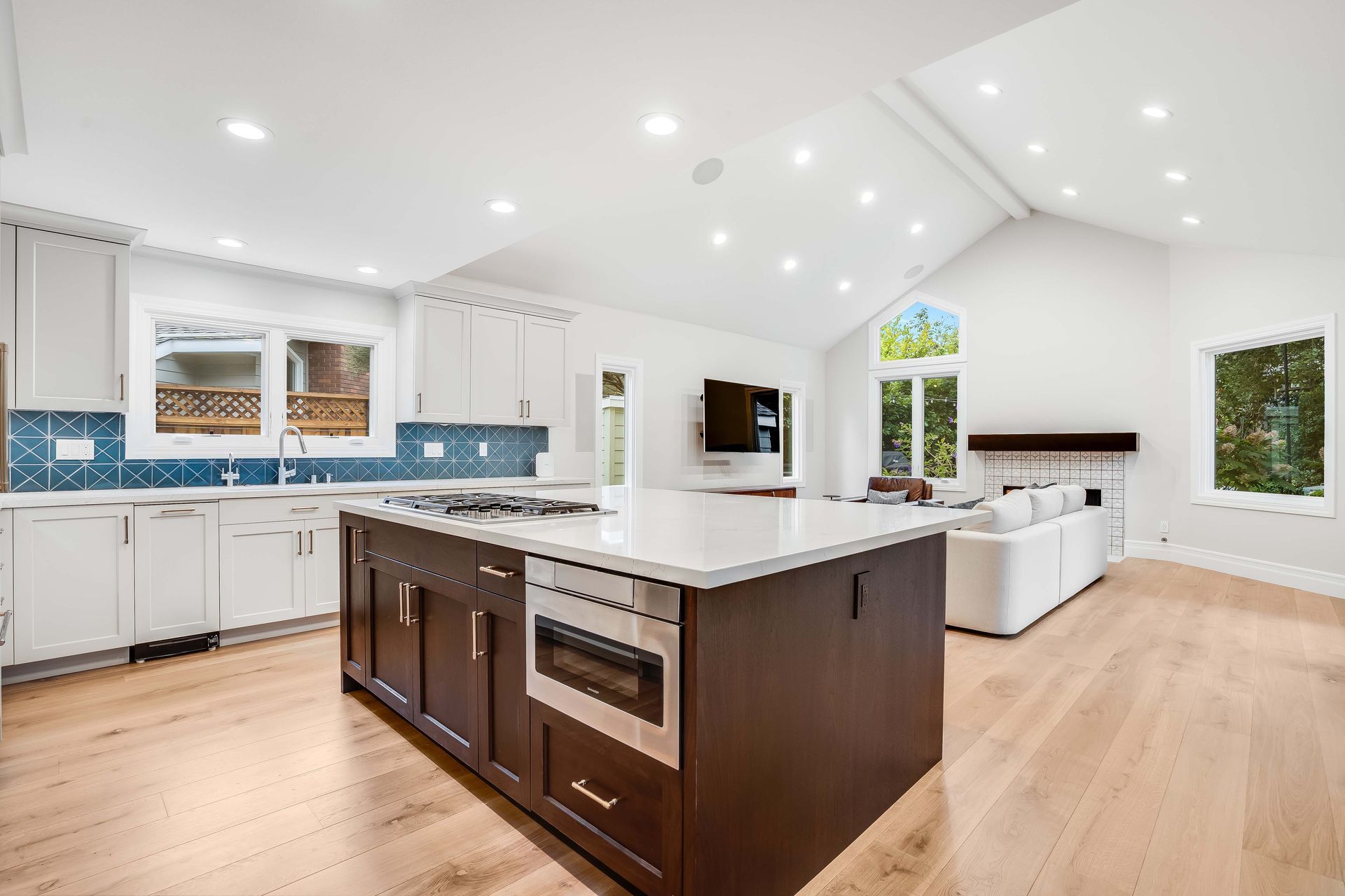 Spacious, bright kitchen with white cabinets, dark island, and a vaulted ceiling.