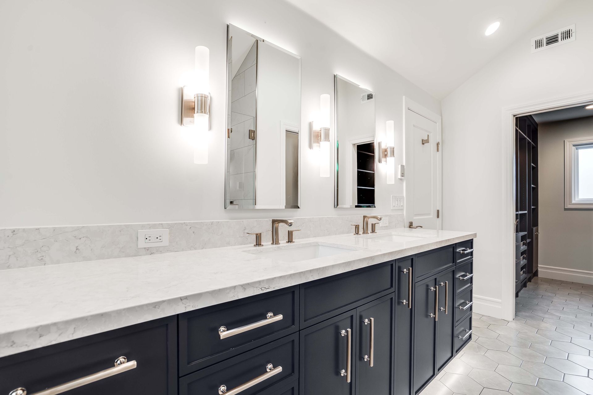Modern bathroom with a navy vanity, white countertops, and three mirrors.
