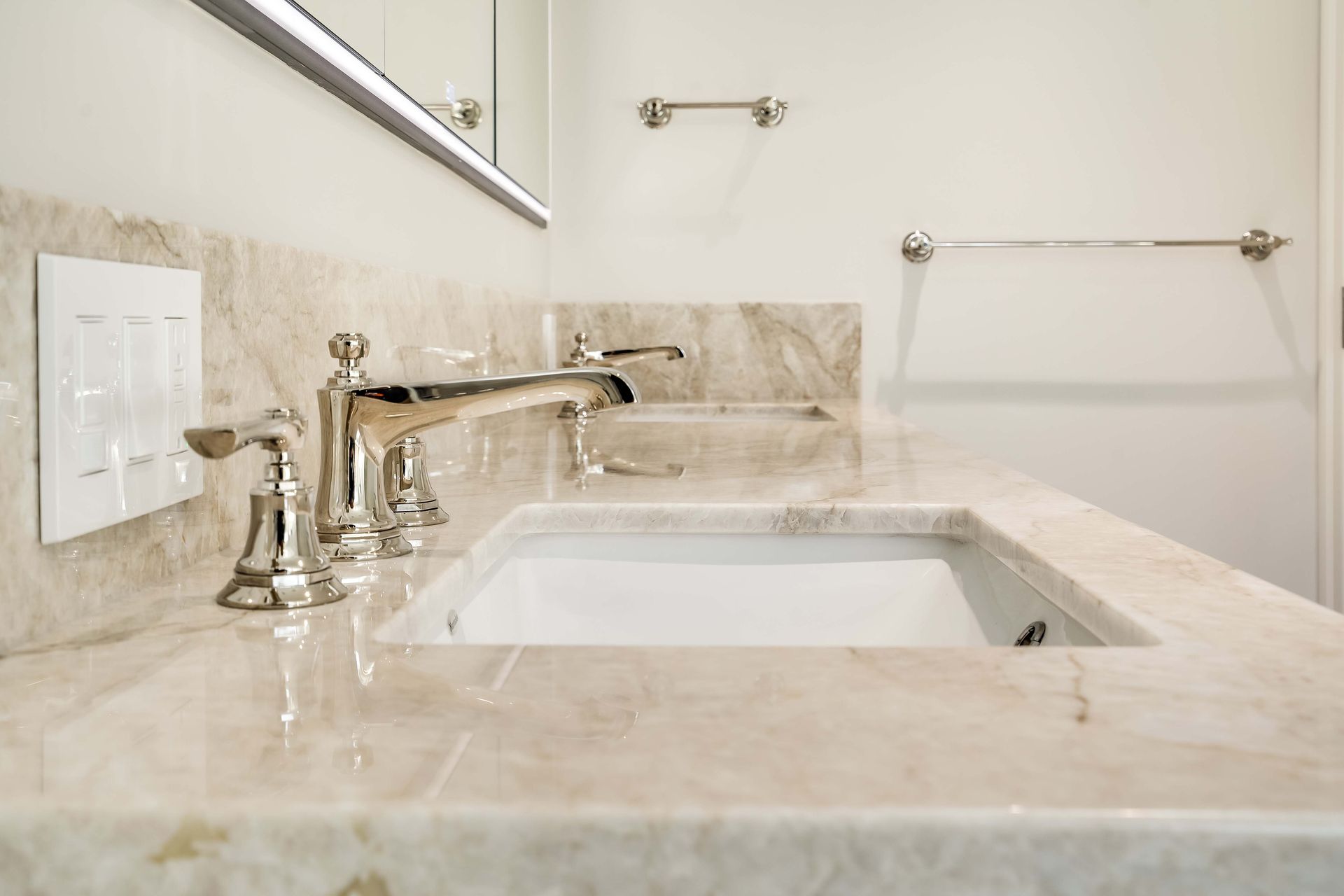 Bathroom sink with marble countertop, silver faucet, and light fixtures.