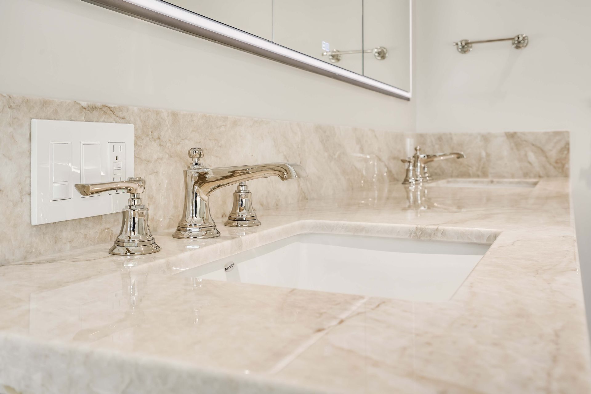 Bathroom vanity with marble countertop and silver faucets, and a recessed sink.