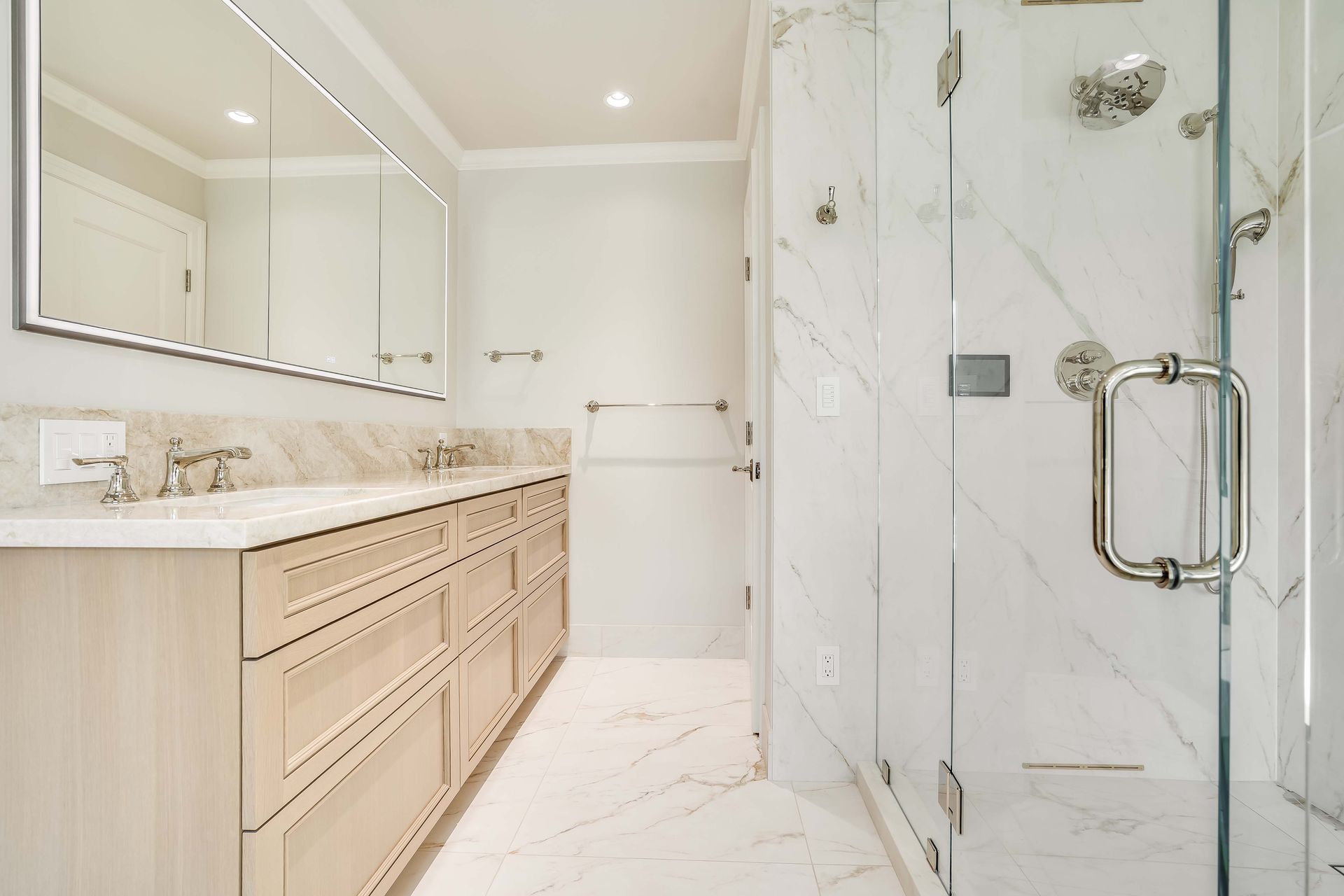 Elegant white marble bathroom with a large glass shower and double vanity.