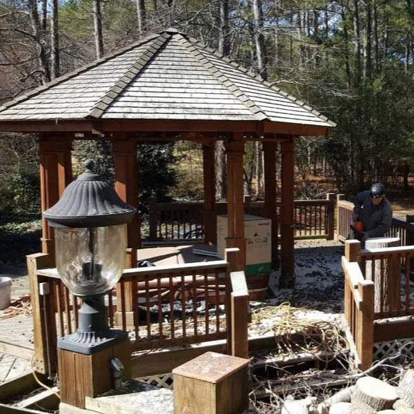 Gazebo on a wooden deck; a person is working nearby.