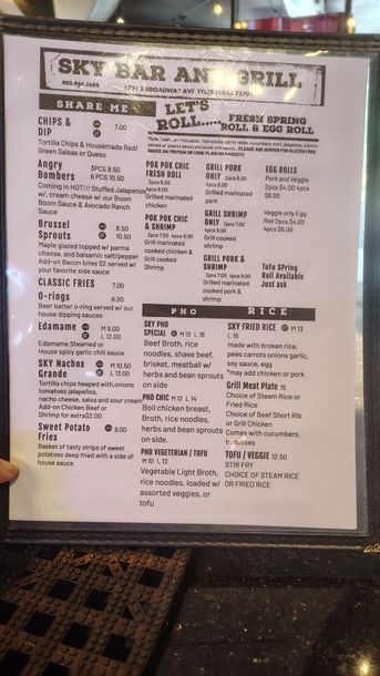 Blurred menu board on a sidewalk, with black text on white paper inside a frame.