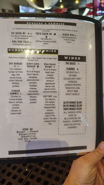 Hand holding a menu with small printed text in a dimly lit restaurant setting