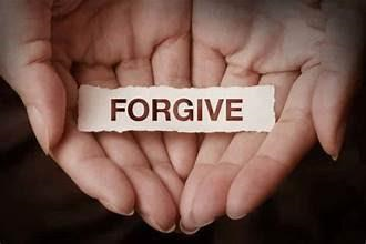 A person is holding a piece of paper that says `` forgive '' in their hands.