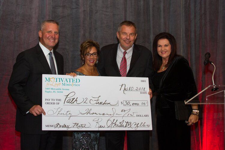 A group of people standing next to each other holding a large check.