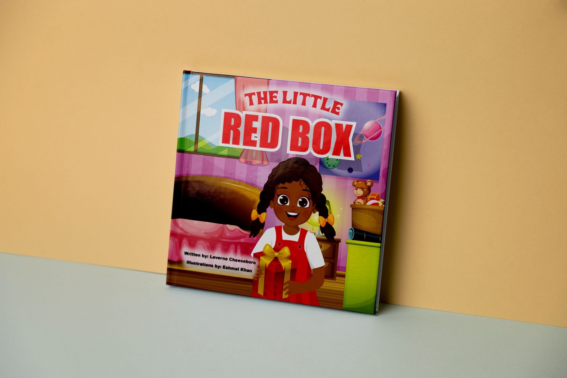A book called the little red box is sitting on a table.