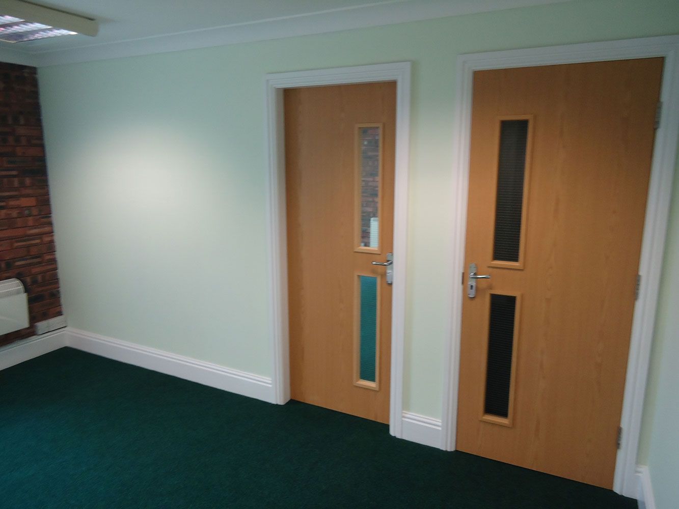A hallway with two doors and a green carpet