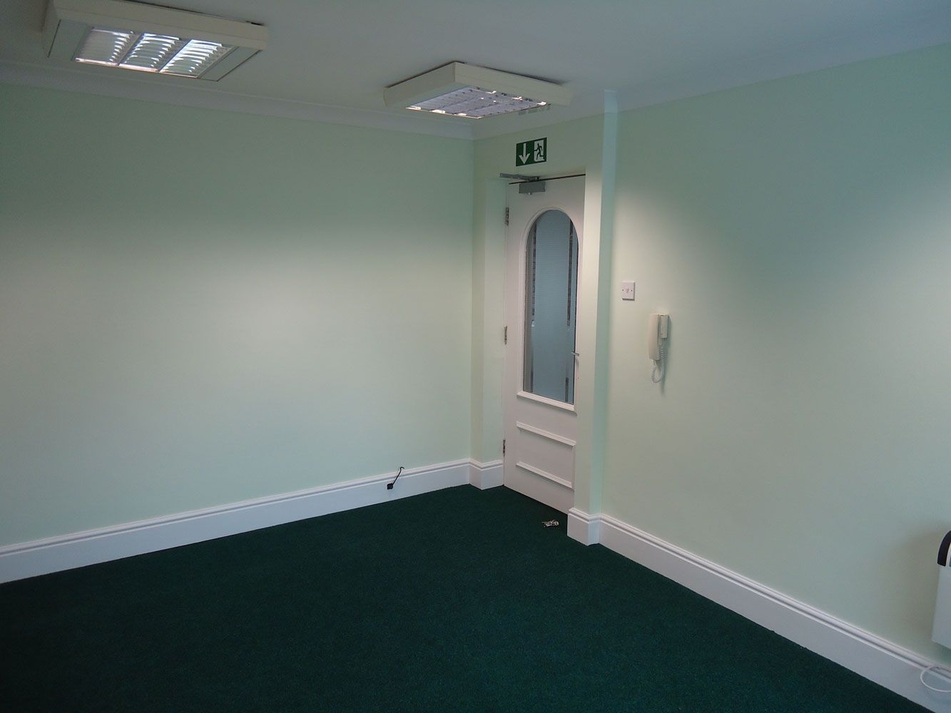 An empty room with green carpet and white walls