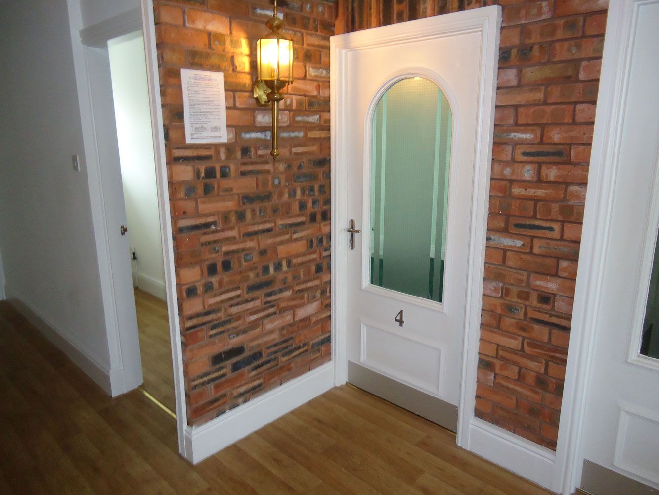 A hallway with a brick wall and a white door with the number 4 on it