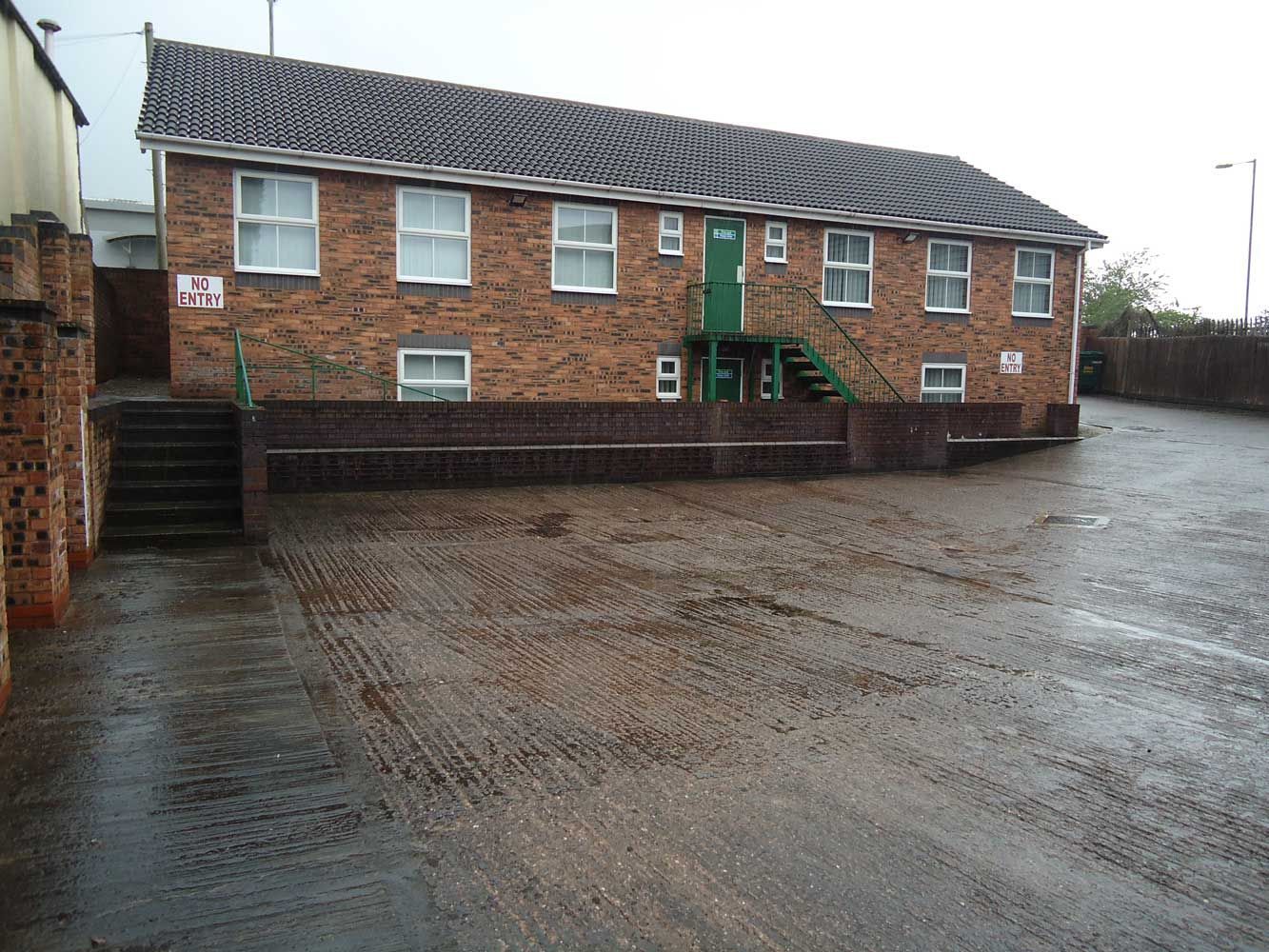 A brick building with a green door and stairs
