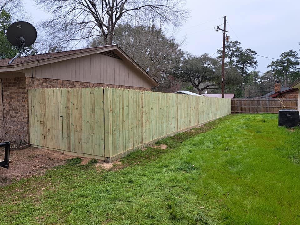 A wooden fence is in the backyard of a house.