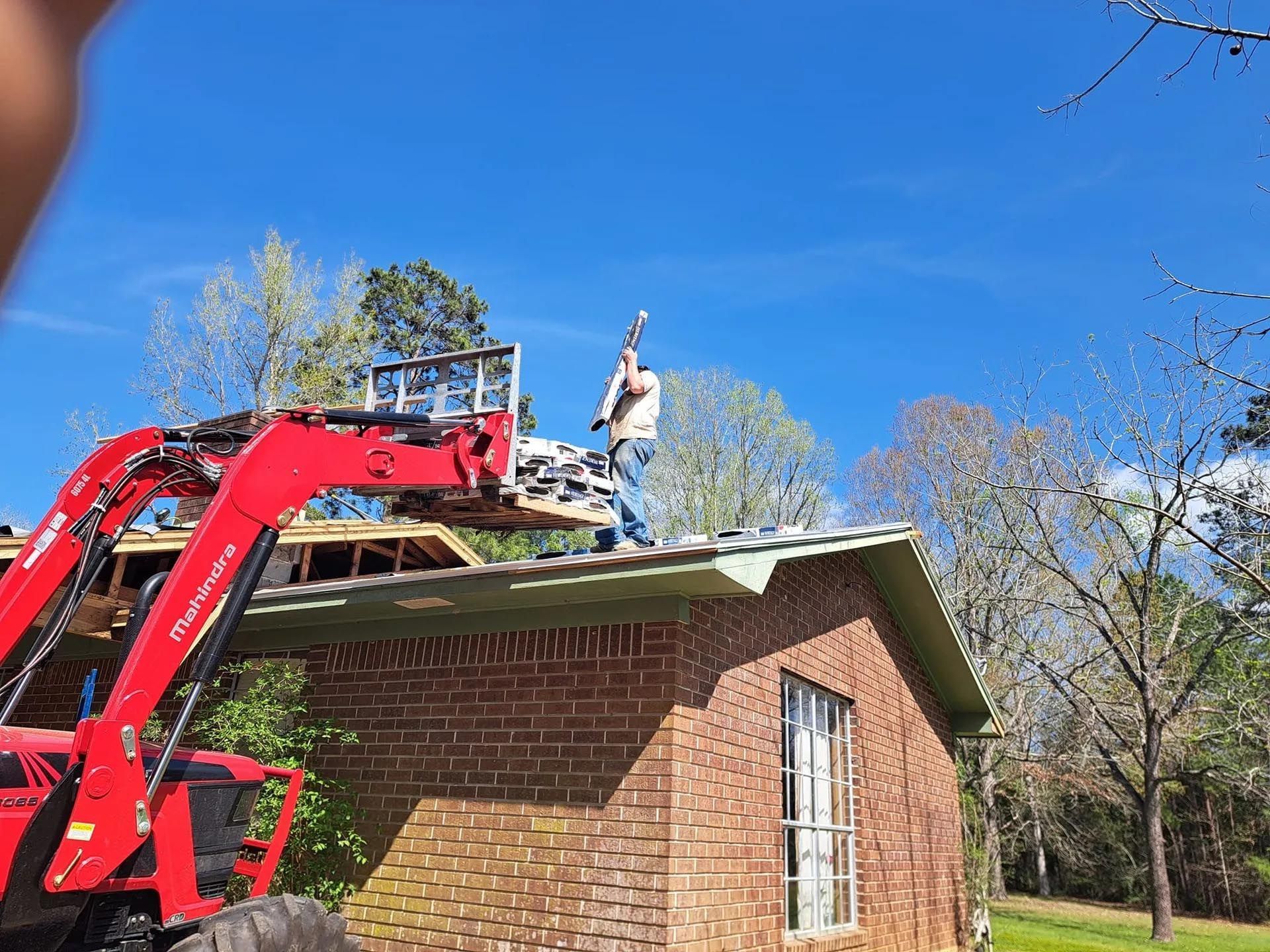 A man is standing on top of a brick building next to a red tractor.