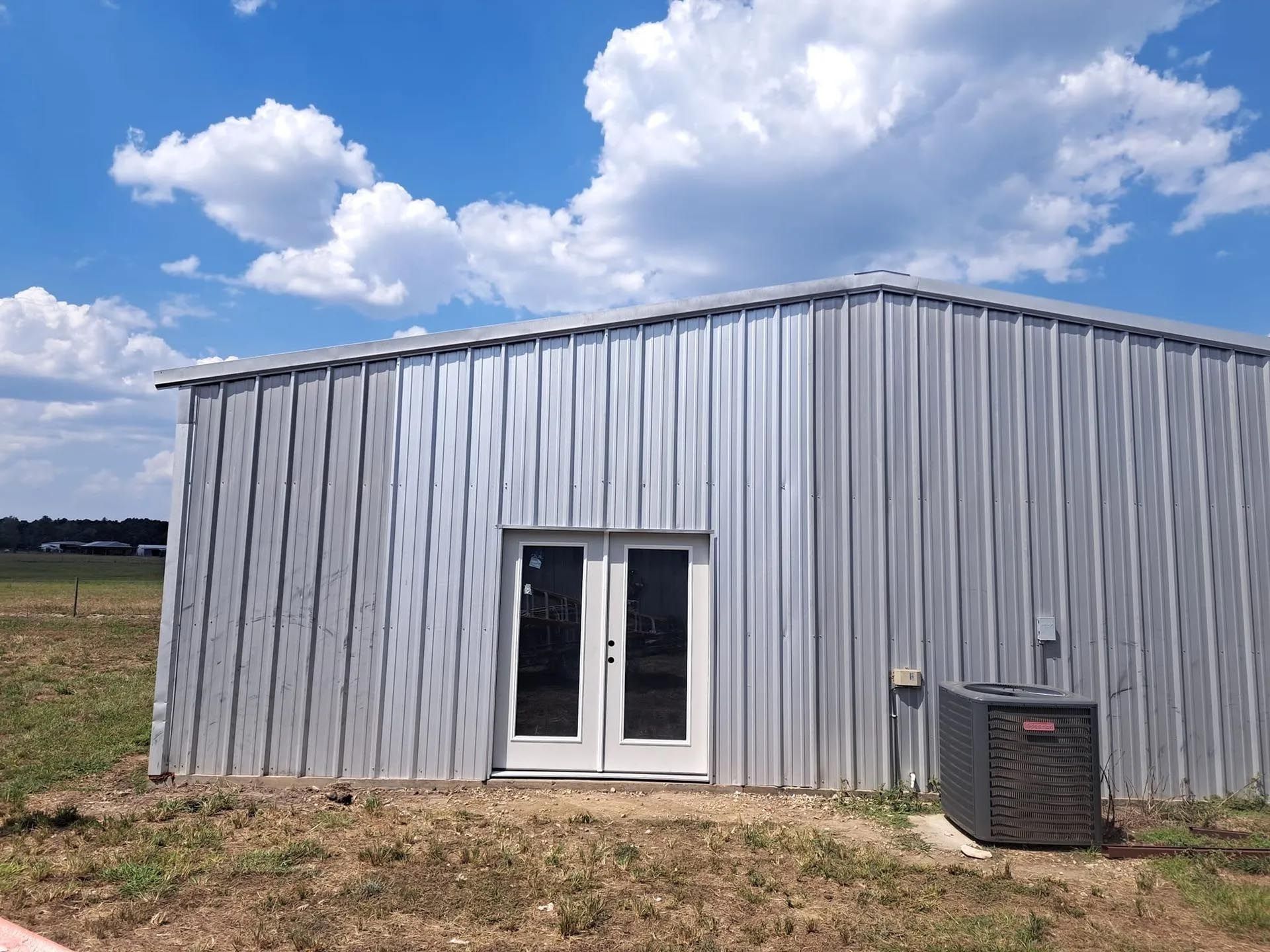 A metal building with two doors and an air conditioner on the side of it.