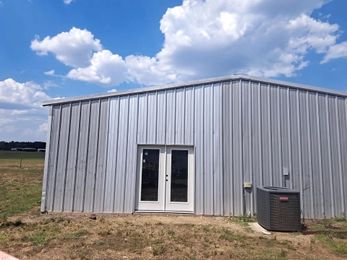 A metal building with two doors and an air conditioner on the side of it.