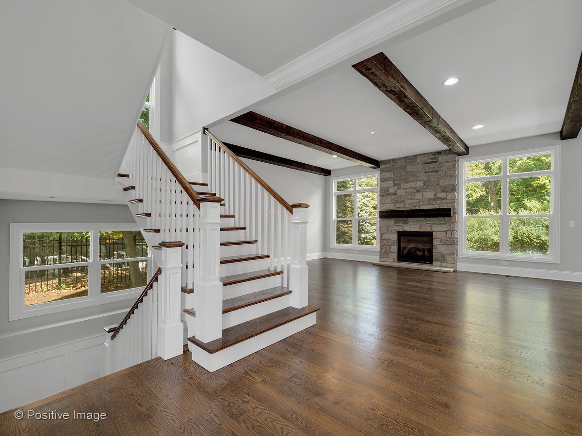 An empty living room with a staircase and a fireplace.