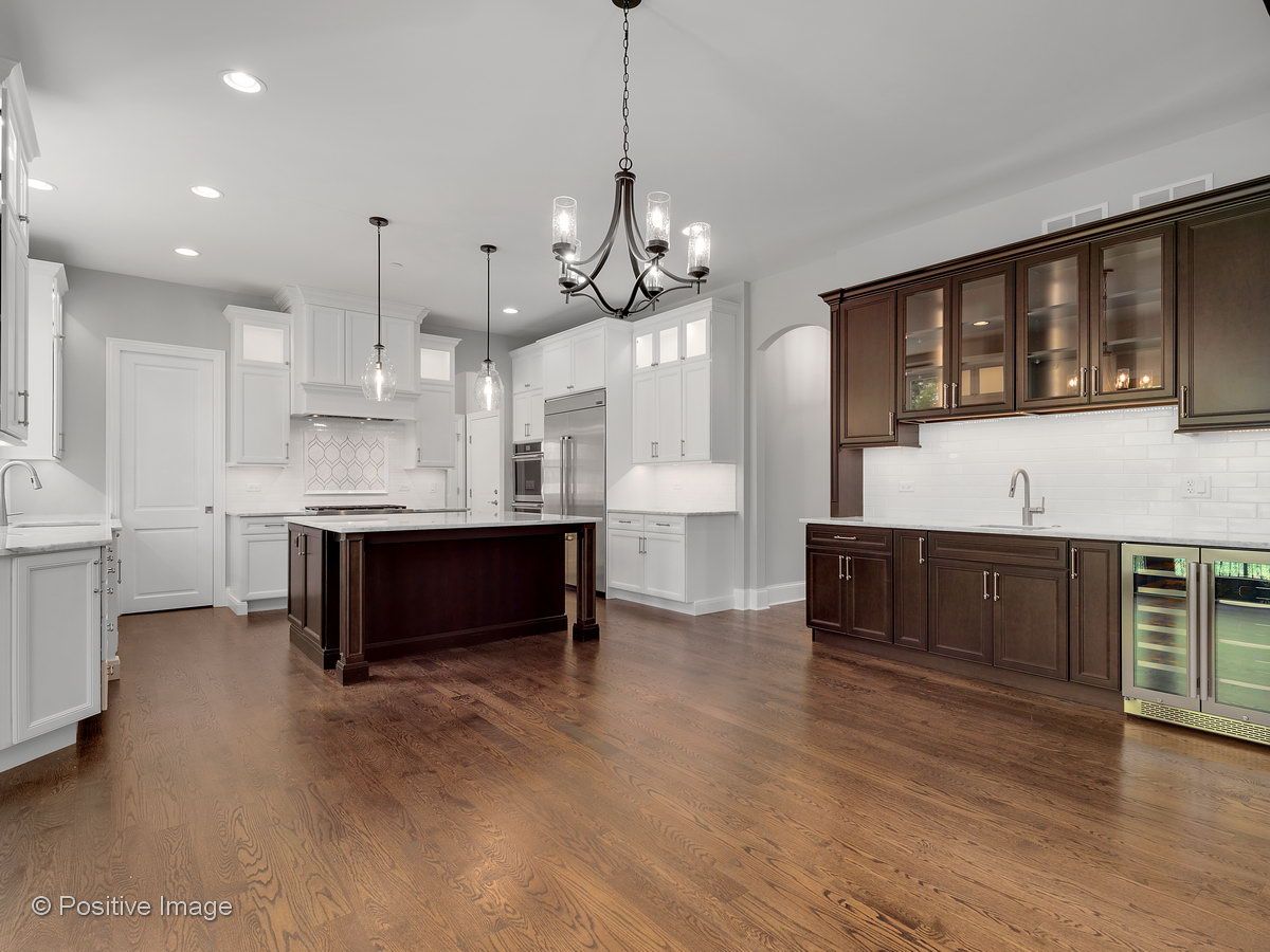 A large kitchen with hardwood floors , white cabinets , and a large island.