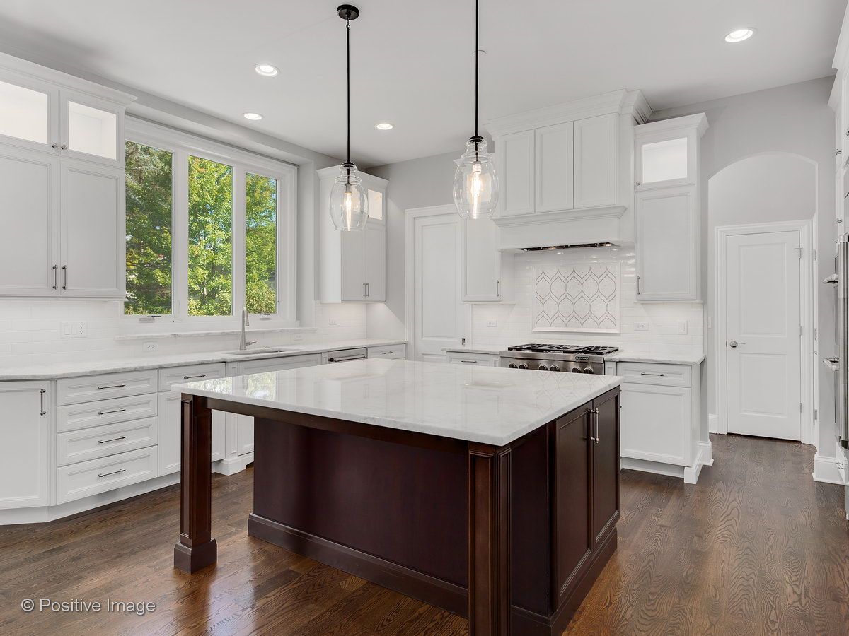 A kitchen with white cabinets and a large island in the middle.