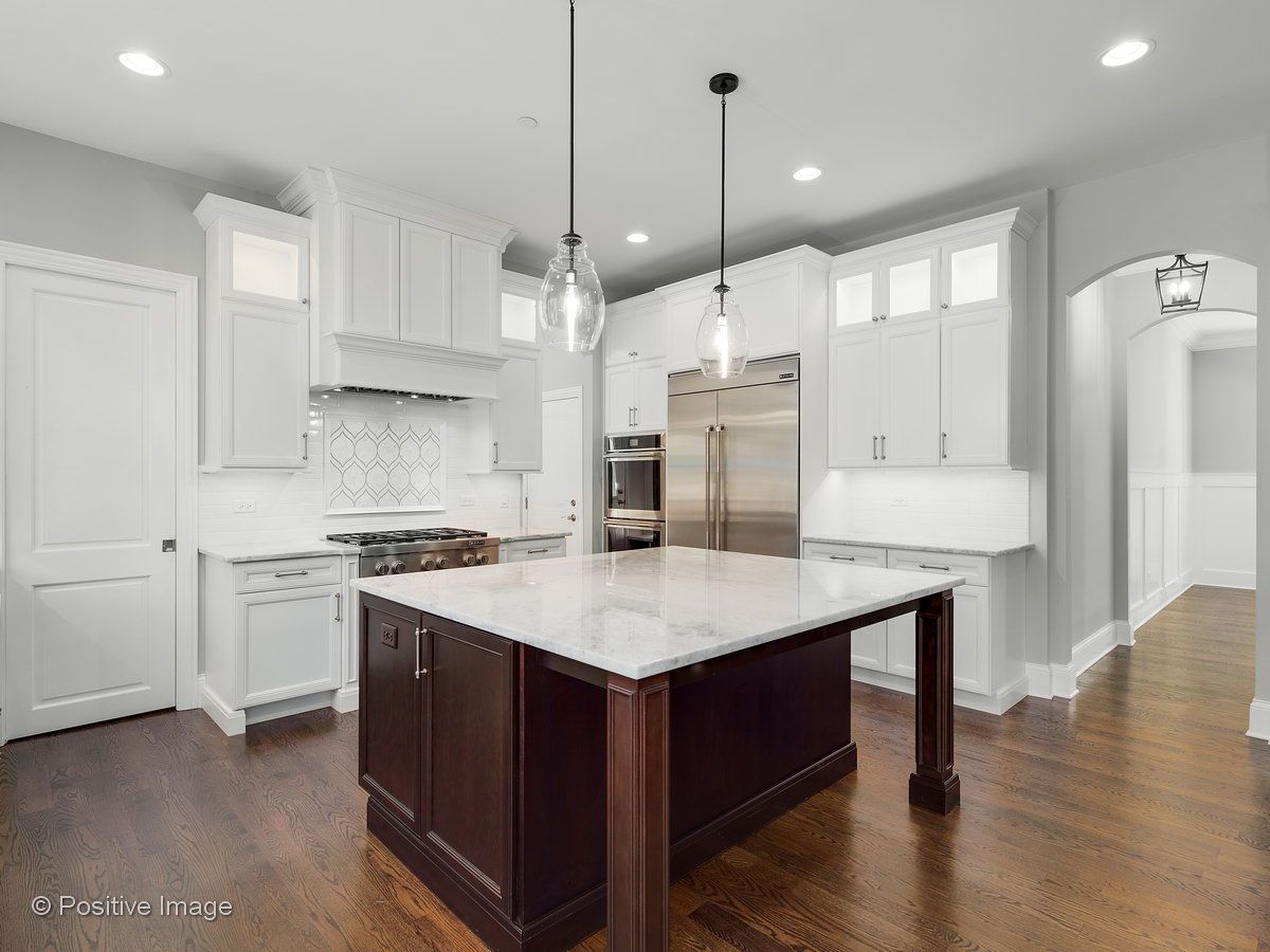A kitchen with white cabinets and a large island in the middle.