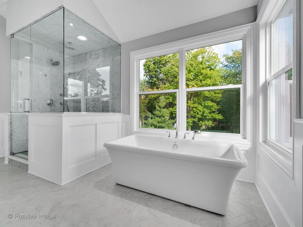 A bathroom with a tub , shower , and window.
