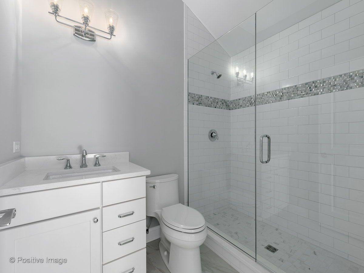 A bathroom with a toilet , sink , and walk in shower.